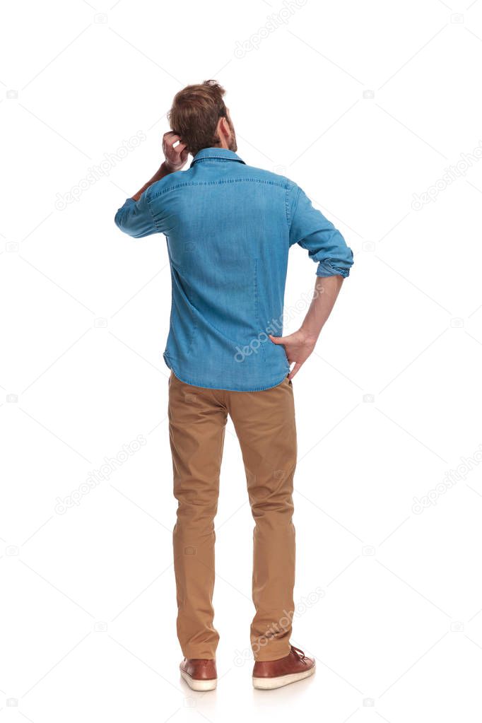 back view of a young casual man scratching his head on white background