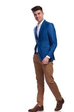 ileri adım ve beyaz arka plan üzerinde kameraya bakarak bir gülümseyen genç casual adam yan görünüm