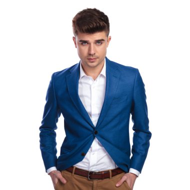 elleri ceplerinde zarif yakışıklı kameraya beyaz arka plan üzerinde görünüyor.