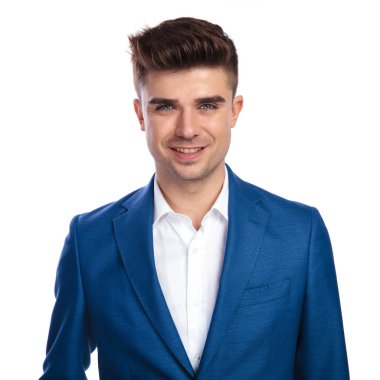 mavi ceket ve beyaz arka plan ayakta beyaz gömlek gülümseyen genç bir adam portresi