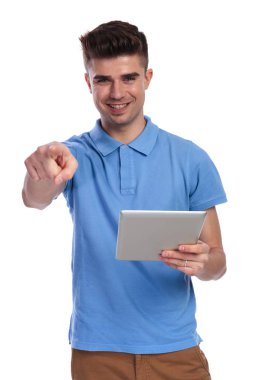 Tablet tutan mutlu casual adam beyaz arka plan üzerinde parmak işaret ediyor