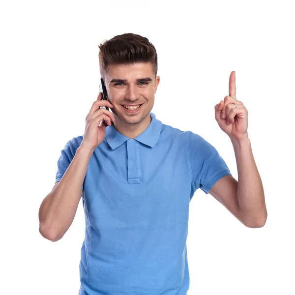 年轻的休闲男子在电话上指着在白色背景上的东西 — 图库照片