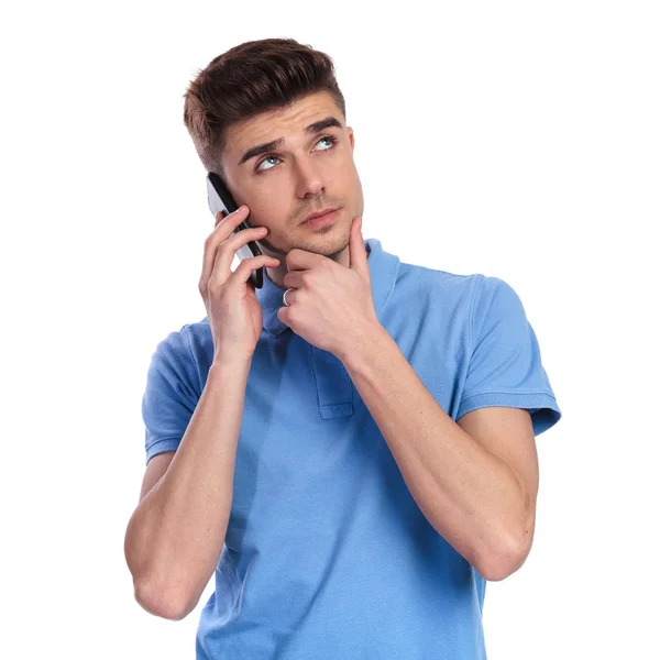 思慮深い若いカジュアルな男が電話で話しては 白い背景の上を検索します — ストック写真