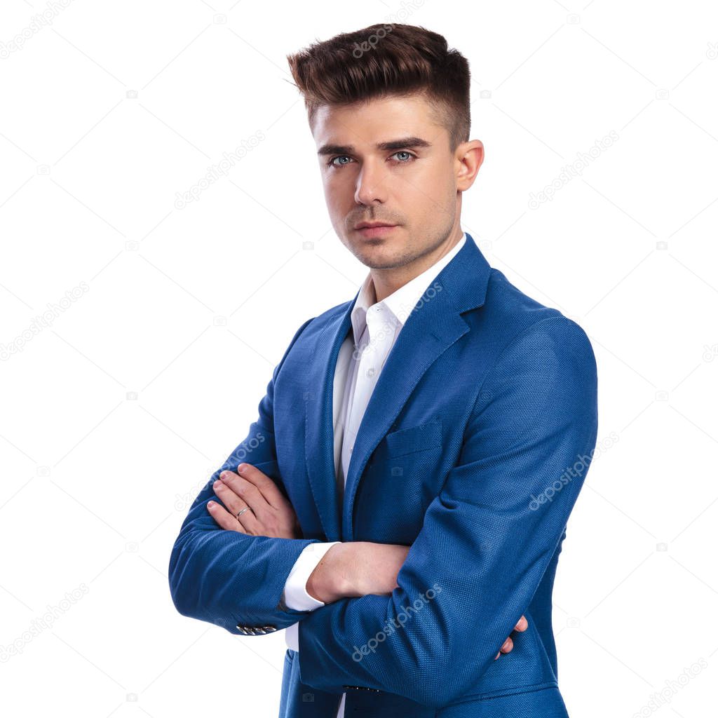 serious young businessman standing with hands crossed on white background