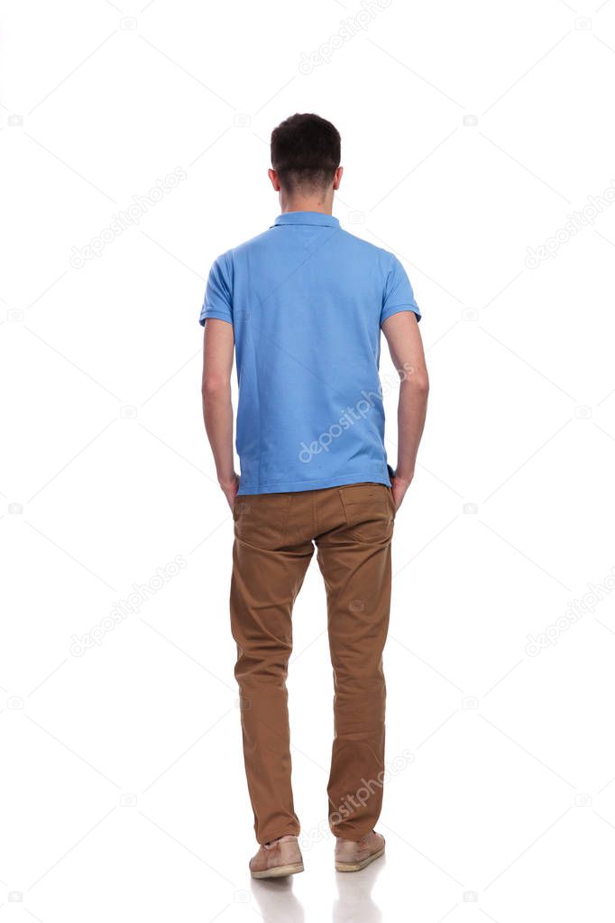 back view of a relaxed casual man standing with hands in pockets on white background