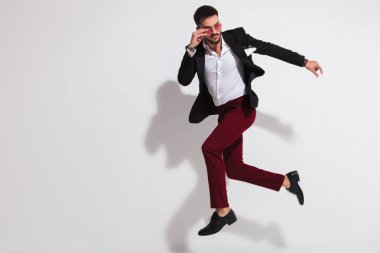 Güneş gözlüklerini sabitleme Akıllı casual adam atlama yan görünüm