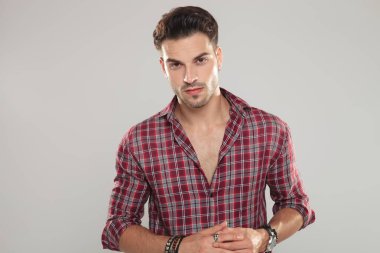 casual adam gri arka plan üzerinde onun parmak yüzük ile oynarken gülümseyen