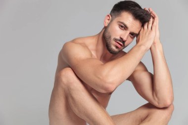 maditating gri arka plan üzerinde oturan çıplak bir adamdır