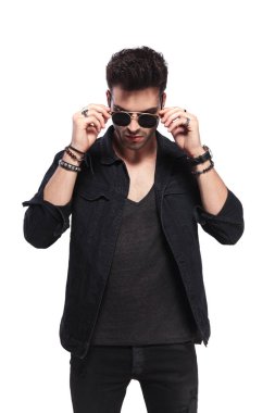 yakışıklı adam aşağı bakıyor ve beyaz arka plan üzerinde ayakta iken güneş gözlüğü sabitleme portresi