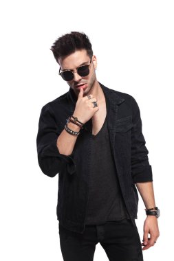 Dudaklarını beyaz arka plan üzerinde dururken dokunaklı siyah giysili baştan çıkarıcı yakışıklı adam portresi