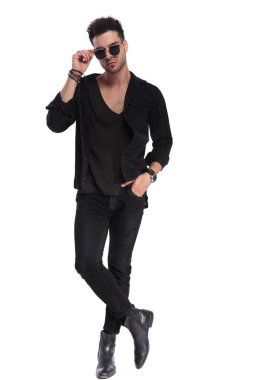 güneş gözlüğü düzenlenmesi ve beyaz arka plan üzerinde tam uzunlukta resim ayakta iken ayakları ile poz siyah giysili rahat rahat adam geçti