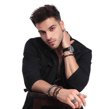 Beyaz arka plan üzerinde ahşap masa üzerine eğilerek boynunu tutarak siyah giysili baştan çıkarıcı adam portresi