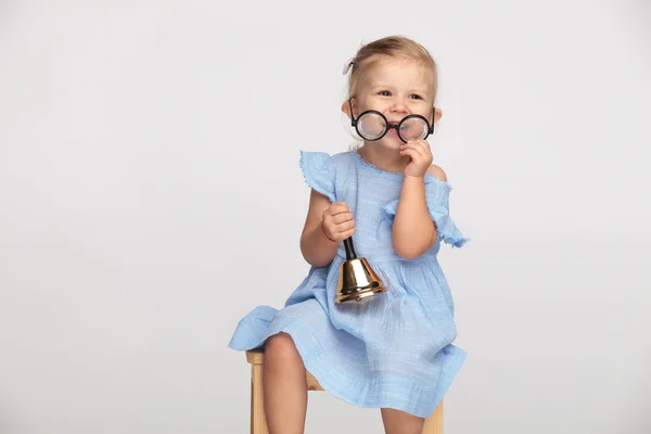 Laughing Little Girl Takes Her Glasses Holds Handbell While Sitting — Stock Photo, Image