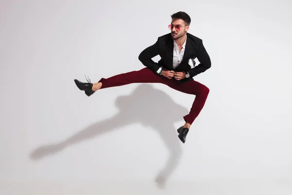 Jumping Young Man Parting His Legs Unbuttoning Black Suit While — Stock Photo, Image