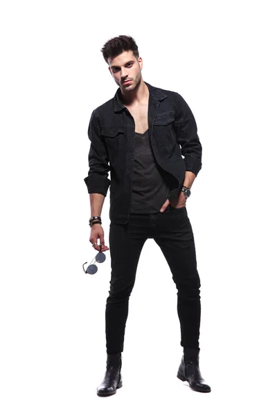 Zrelaksowany Młody Człowiek Czarne Ubrania Stojąc Tle Gospodarstwa Okulary Szukam — Zdjęcie stockowe