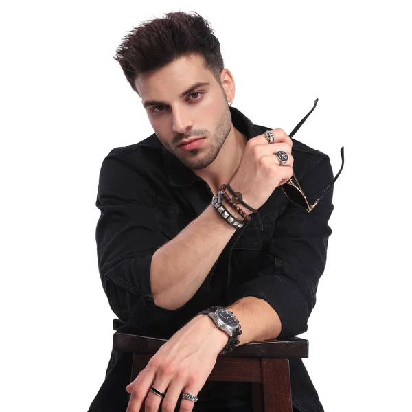 Retrato Joven Vestido Negro Sosteniendo Gafas Sol Apoyado Mesa Mientras — Foto de Stock