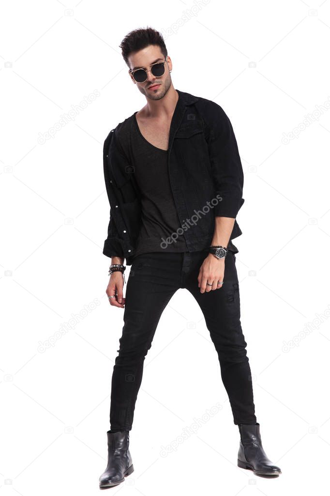 dominant man in black clothes standing on white background with parted legs, full length picture