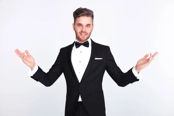 Homem Elegante Smoking Fazendo Gesto Boas Vindas Enquanto Sobre Fundo — Fotografia de Stock