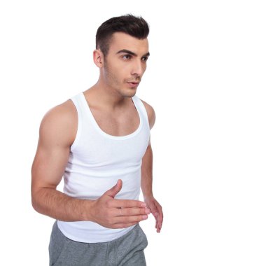 Beyaz arka plan üzerinde çalışan ve tarafına bakarak fanila genç uygun adam portresi