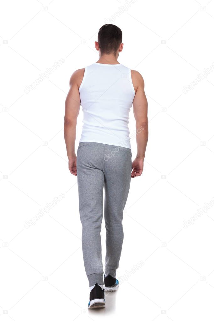 back view of young fit man in undershirt stepping on white background, full length picture