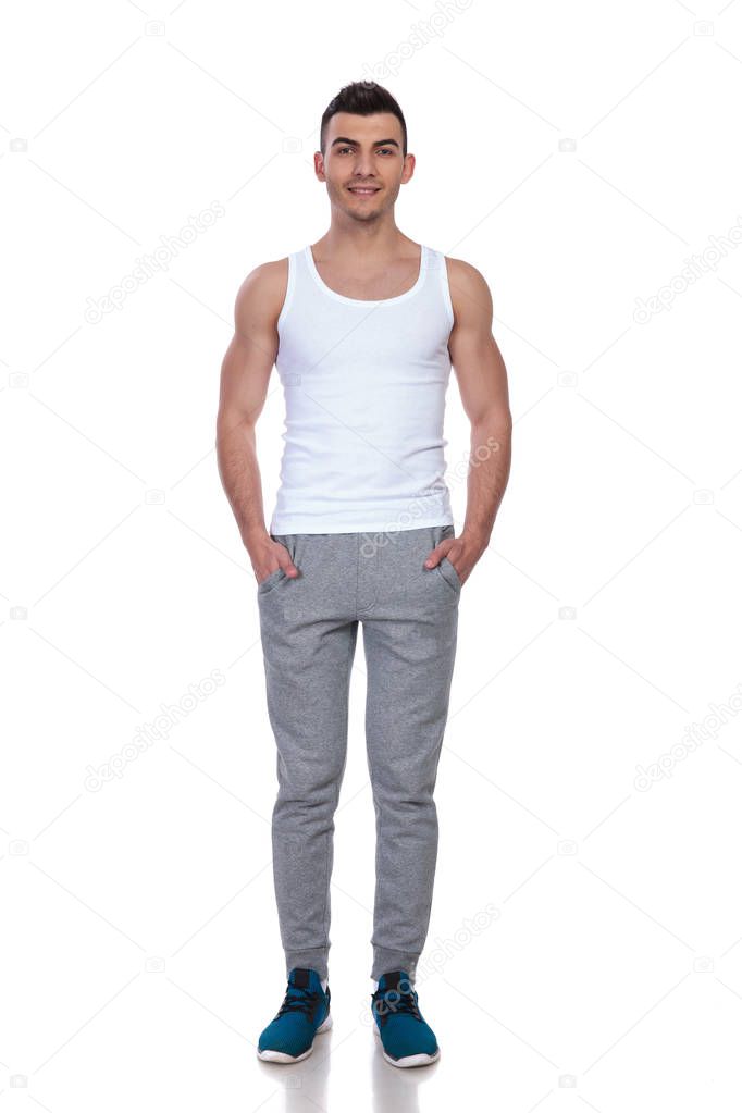 handsome man wearing white top standing with hands in pockets on white background, full length picture