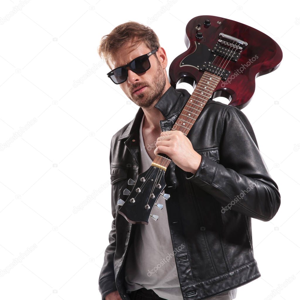 portrait of cool rock star with sunglasses holding his guitar on shoulder while standing on white background