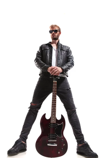 宽角度的主导吉他手穿着黑色的皮革夹克和太阳镜持有他的电吉他 而站在白色背景 — 图库照片