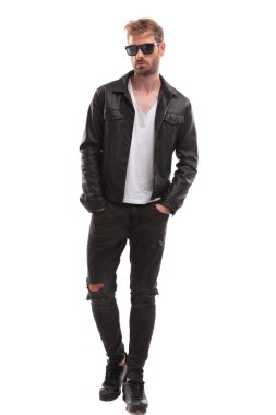 güneş gözlüğü ve beyaz zemin üzerine yürüyen siyah deri ceket giyiyor rahat moda adam cepler ve tarafına arıyor eller