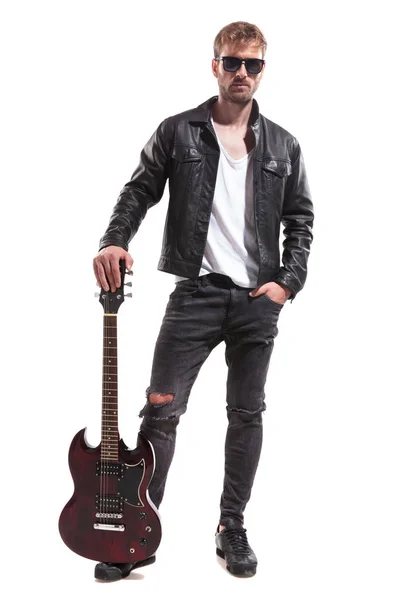宽松的时尚男人穿着黑色的皮革夹克和太阳镜摆在他的电吉他 而站在白色背景 — 图库照片