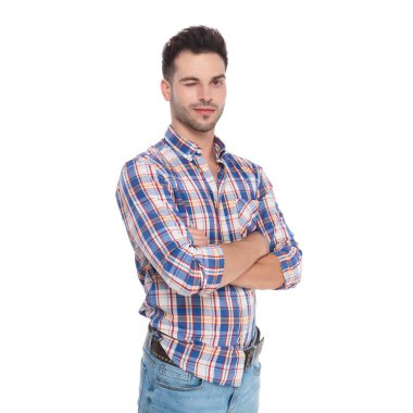 ekose gömlek kolları olan beyaz arka plan üzerinde dururken göz kırpıyor giyen kendine güvenen adam portresi katlanmış