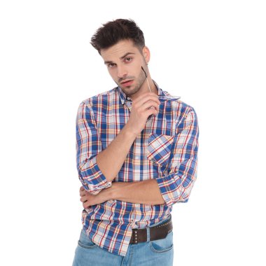 mavi dama beyaz arka plan üzerinde duran güneş gözlüğü holding ile gömlek giymiş baştan çıkarıcı casual adam portresi