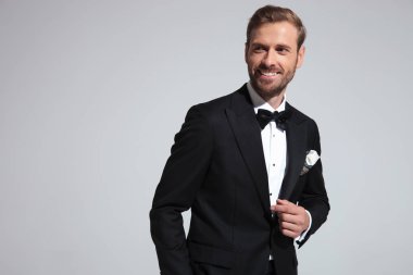 mutlu genç zarif adam gülümsüyor ve tarafına gri arka plan üzerinde görünüyor