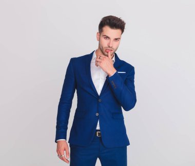 mavi elbiseli dudakları hafif gri arka plan üzerinde dururken dokunmadan baştan çıkarıcı adam portresi