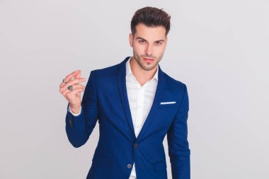 mavi elbiseli ışık gri arka plan üzerinde parmaklarını dururken yapışma akıllı casual adam portresi