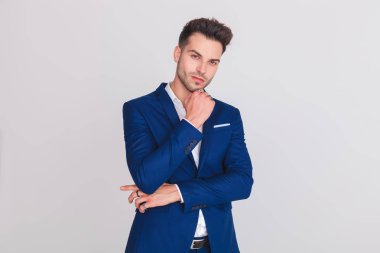 Mavi takımı ayakta hafif gri arka plan üzerinde giyen dalgın genç adam portresi