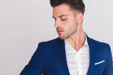 Yan ışık gri arka plan üzerinde dururken görünen baştan çıkarıcı akıllı casual adam portresi