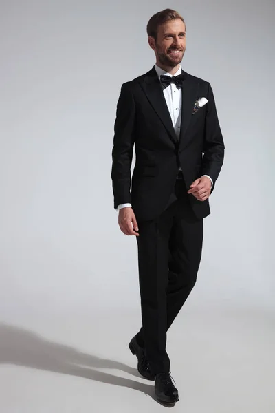 Sonriente Joven Elegante Hombre Camina Traje Esmoquin Sobre Fondo Gris — Foto de Stock