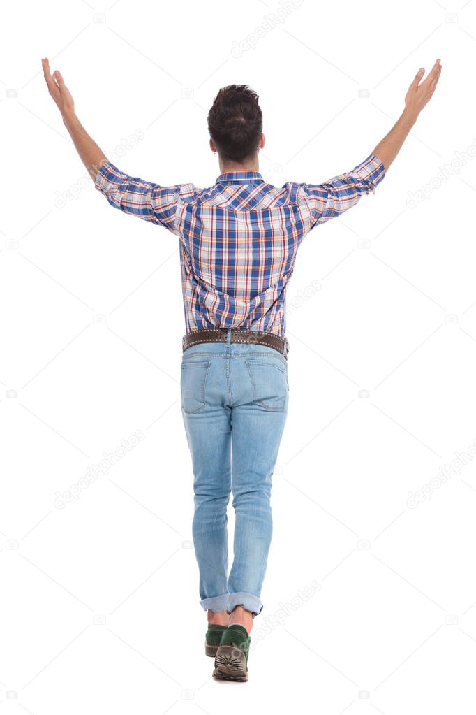 rear view of casual man celebrating and stepping on white background while looking up, full length picture