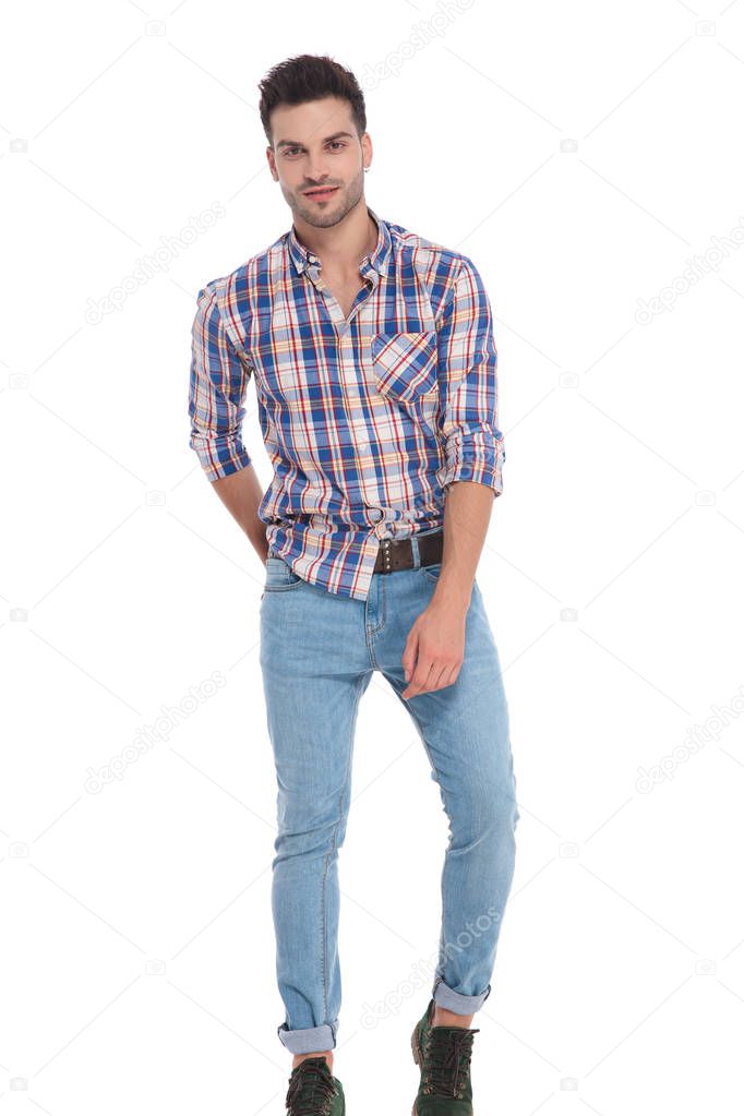 smiling man wearing checkered shirt and jeans standing on white background, full length picture
