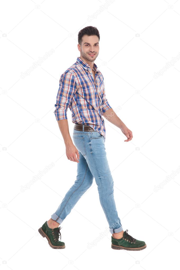 side view of casual man wearing shirt with red plaids stepping on white background, full body picture