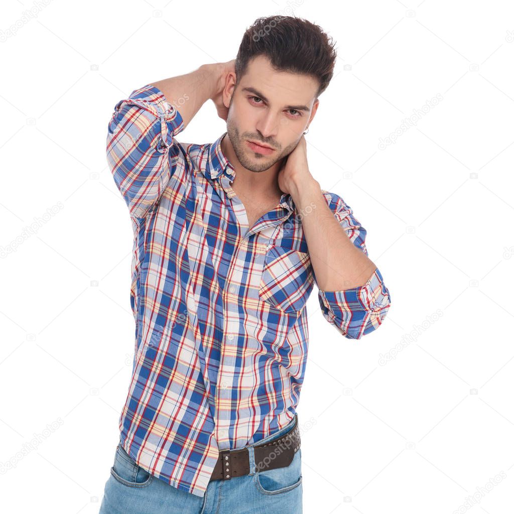 portrait of young man holding his neck in sensual pose while standing on white background