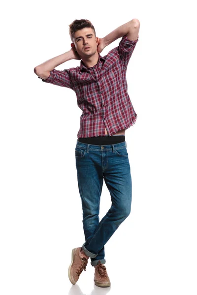 官能的な男のジーンズとチェック柄のシャツを着て首を保持は 一方の足で立っている白い背景のフルの長さの画像上を越え — ストック写真