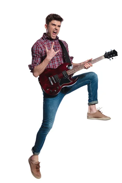 若い男がエレク トリック ギターの叫びと白い背景 全身画像でジャンプしながら作る角記号 — ストック写真