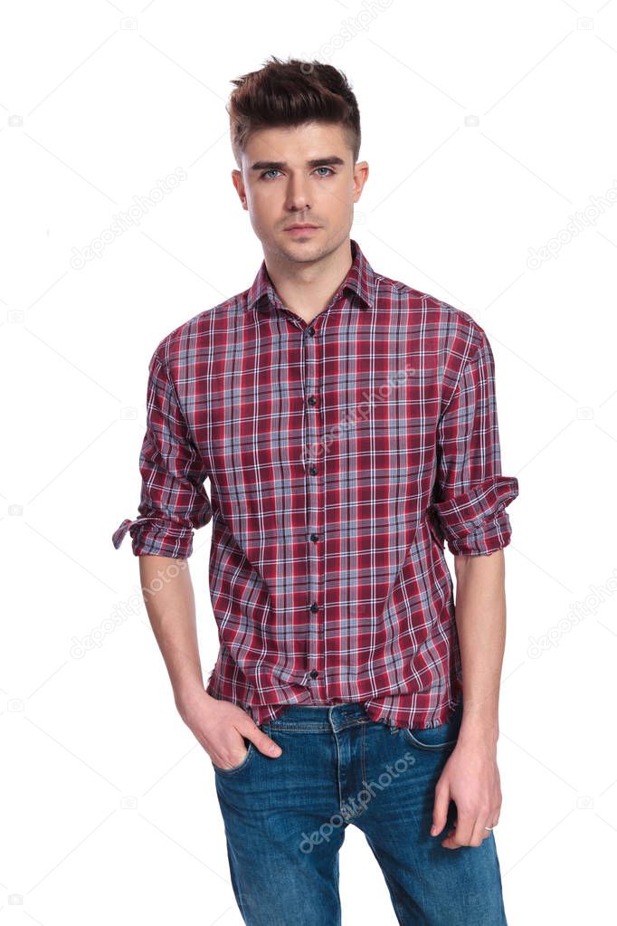 portrait of relaxed young man wearing a shirt with plaids while standing on white background with hands in pockets