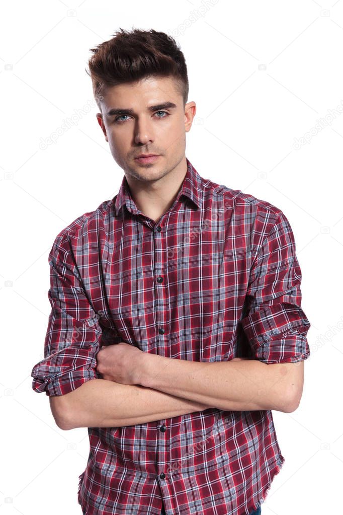 portrait of handsome casual man wearing a shirt with red checkers standing with arms folded on white background