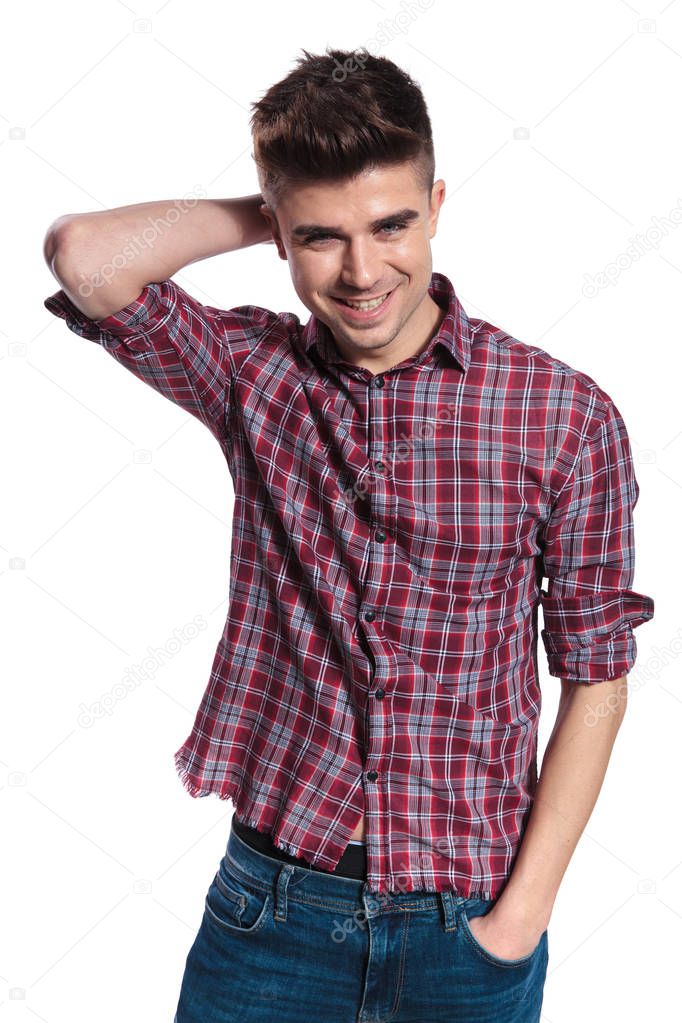 portrait of relaxed casual man holding neck and smiling while standing on white background with hands in pockets