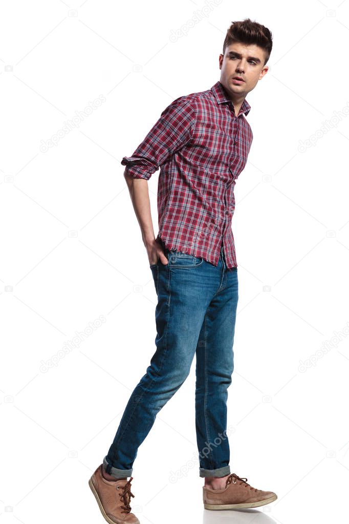 relaxed casual man wearing jeans walks on white background with hands in back pockets and looks to side, full body picture