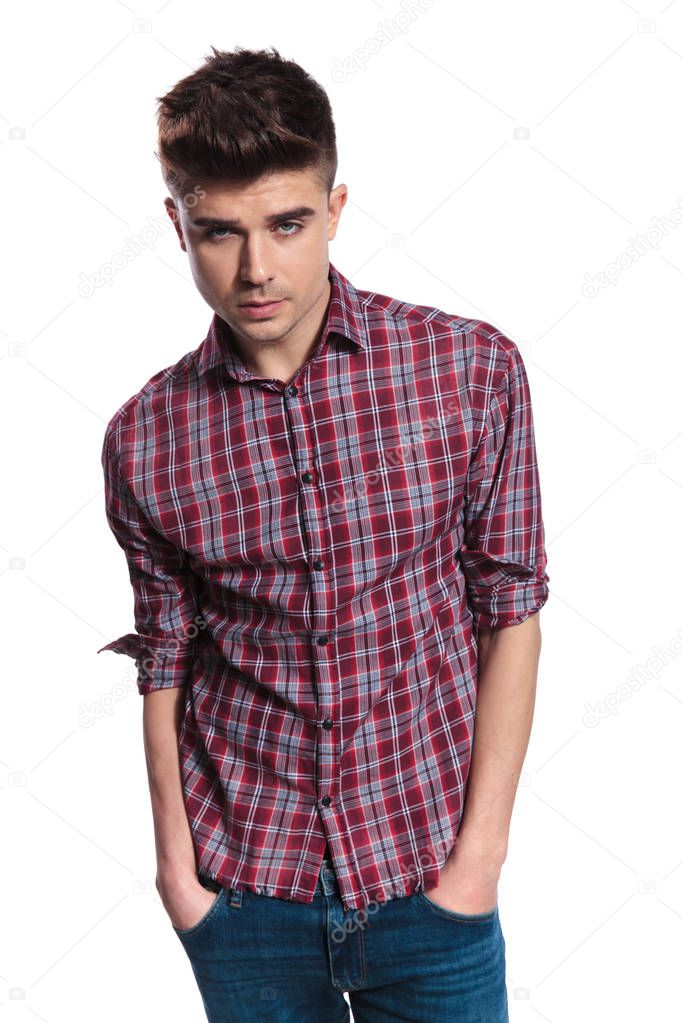 portrait of sensual man with plaid shirt holding pockets while standing on white background
