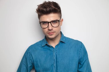 ışık gri arka plan üzerinde durup gözlüklü çekici casual adam portresi