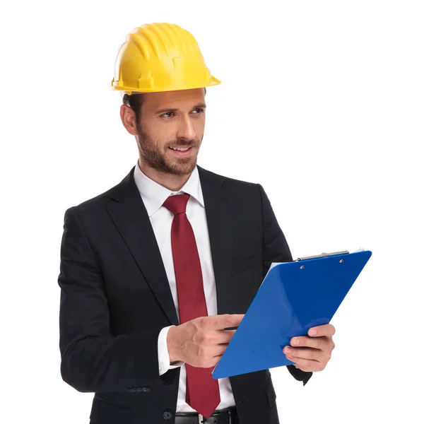 Young Engineer Ceo Holding Blue Clipboard Looks Side While Standing — Stock Photo, Image